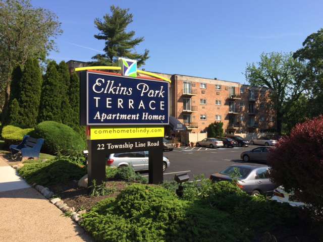 Exterior view of Elkins Park Terrace apartments surrounded by trees and the parking lot