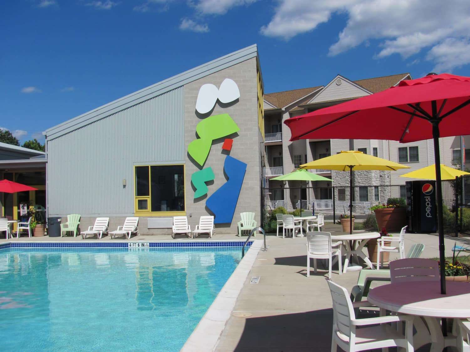 Outdoor pool with lounge chairs and umbrellas at The Enclaves at Packer Park apartments for rent