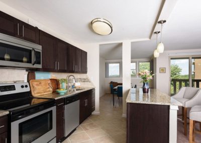 Kitchen with an island. Dark brown cabinets, tan granite countertops, and silver appliances.