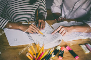 Two students doing homework while using pencils and highlighters