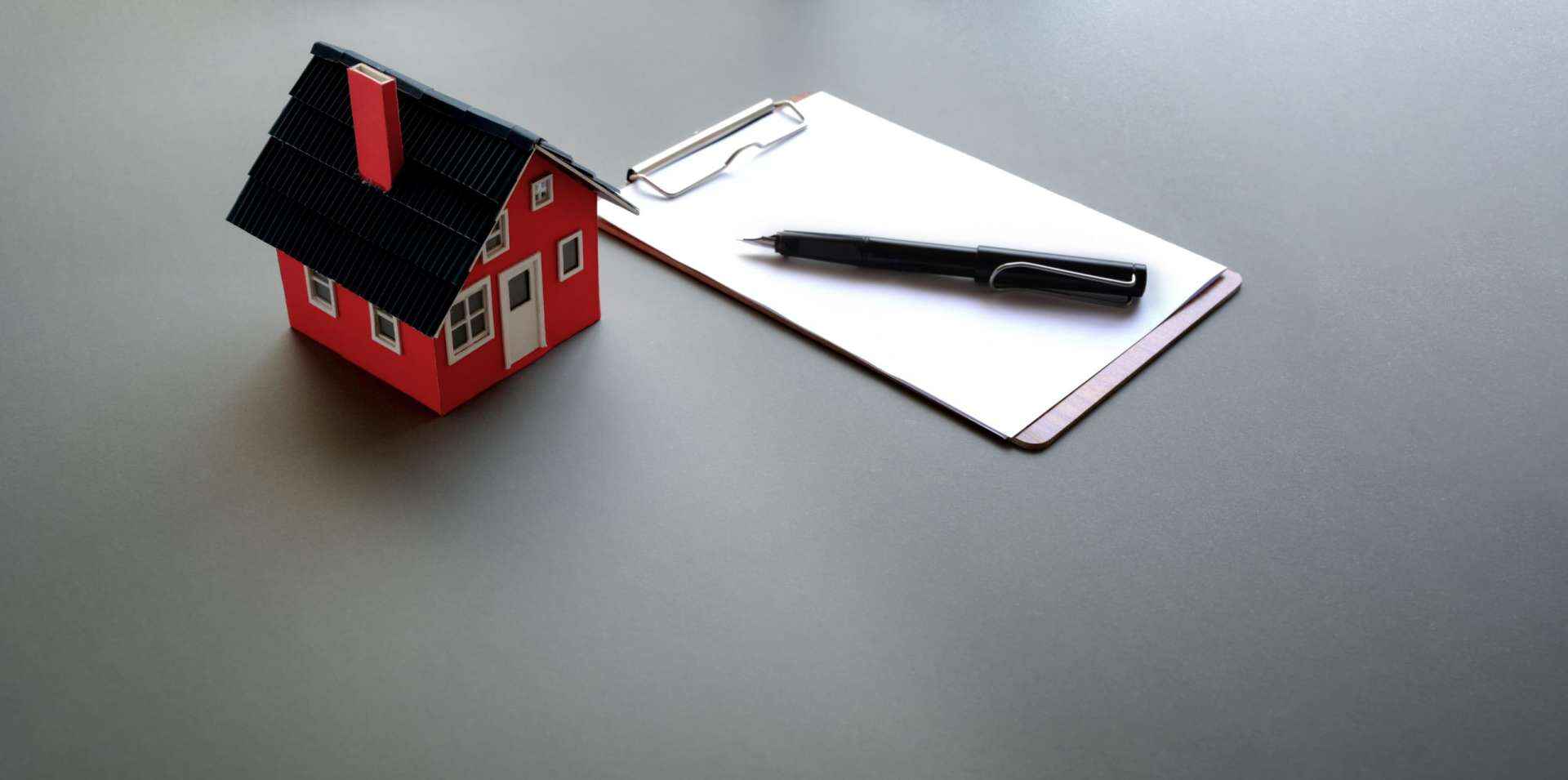 Small model of a house next to a clipboard