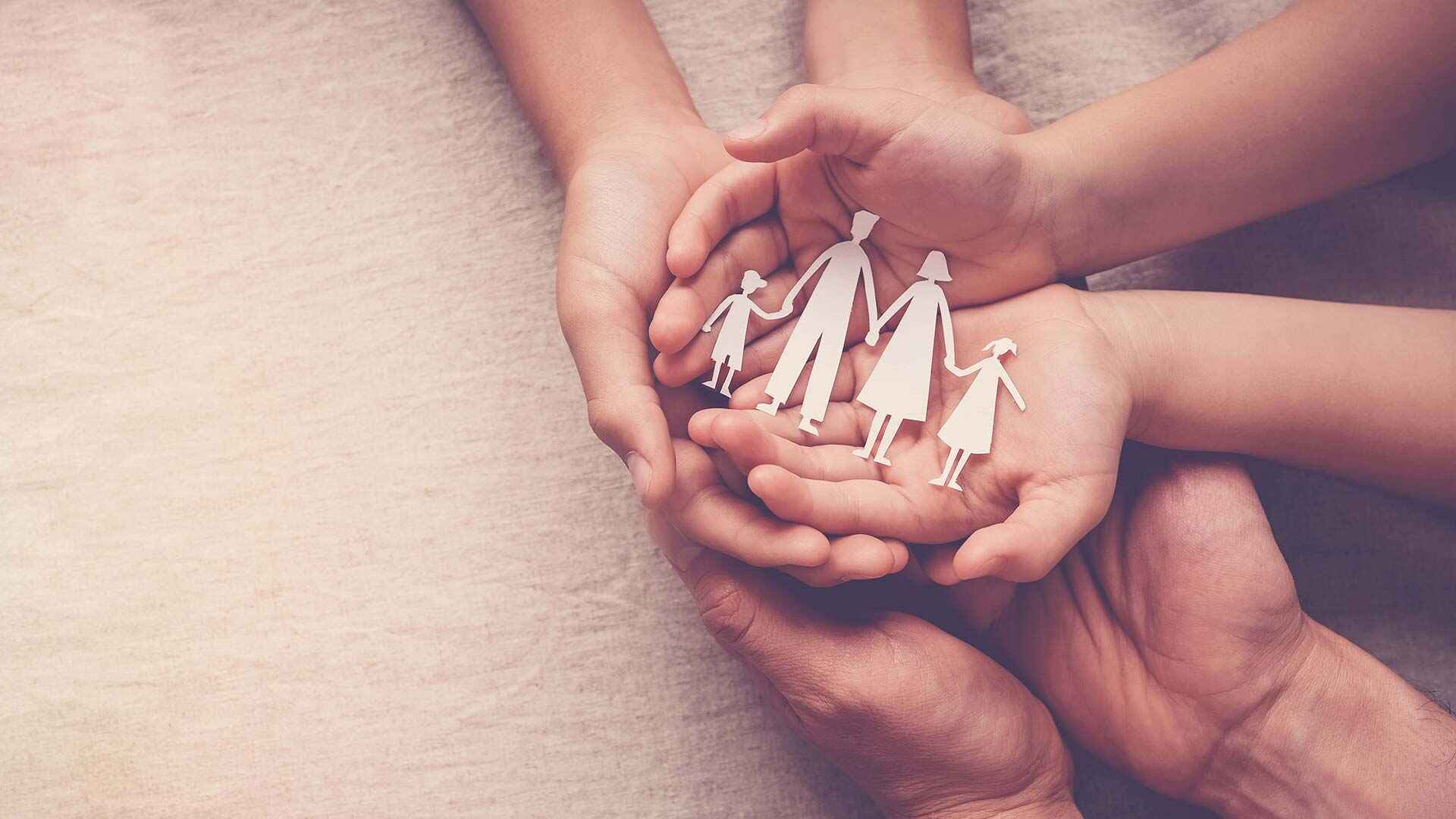 Hands holding paper cutout of a family