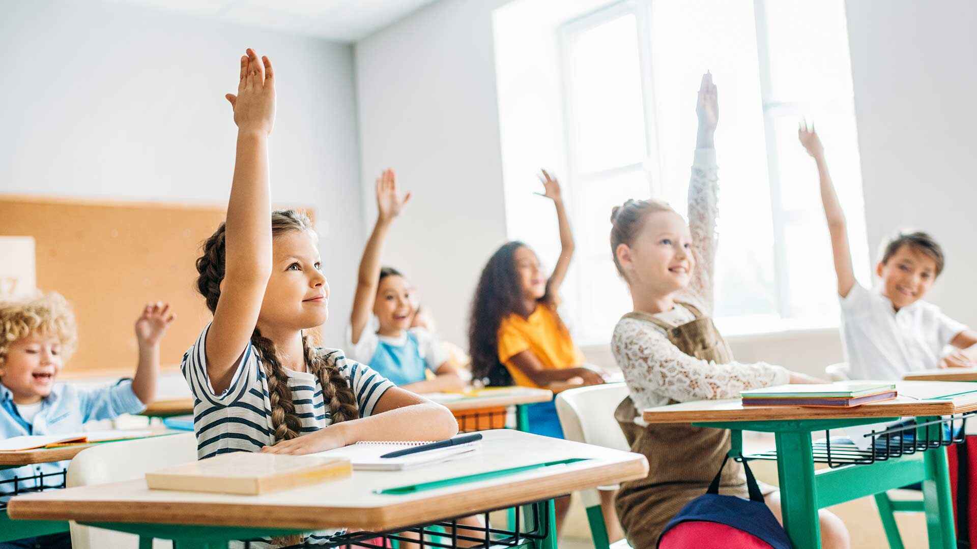 Students in a classroom raising their hands