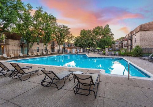 An outdoor pool with lounge chairs and umbrellas with a beautiful sunset at 450 Green apartments