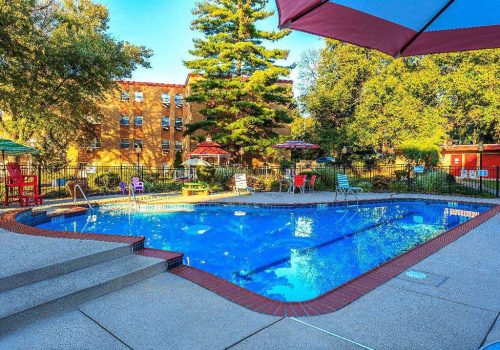 Outdoor pool with lounge chairs and umbrellas at Bromley House apartments for rent