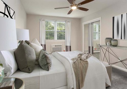 Bed with a ceiling fan and an open window at Gardens of Mt. Airy apartments for rent