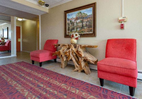 Lobby with two red chairs and a painting at Longwood Manor apartments for rent in Philadelphia, PA