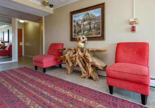 Lobby with two red chairs and a painting at Longwood Manor apartments for rent in Philadelphia, PA