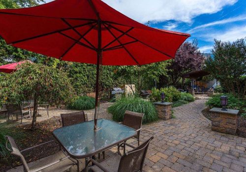 Outdoor lounge area with tables and red umbrellas at The Enclaves at Packer Park apartments for rent