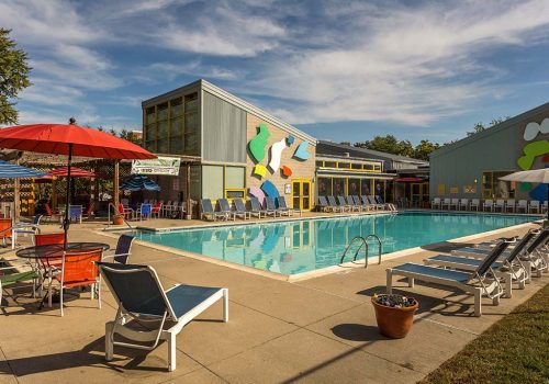 An outdoor pool with lounge chairs and umbrellas at Enclaves at Packer Park apartments for rent