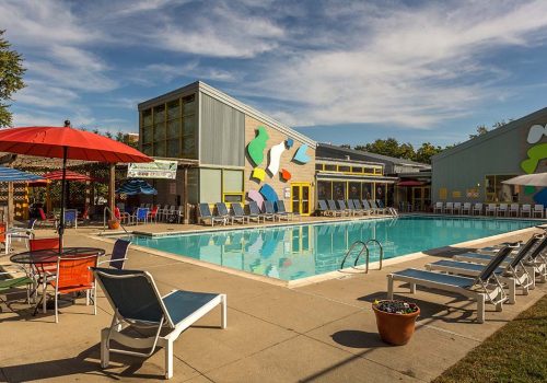 Outdoor pool with lounge chairs and colorful umbrellas at The Gateway Towers at Packer Park