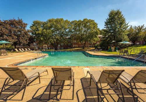 Outdoor pool with lounge chairs and umbrellas at Warrington Crossings apartments for rent