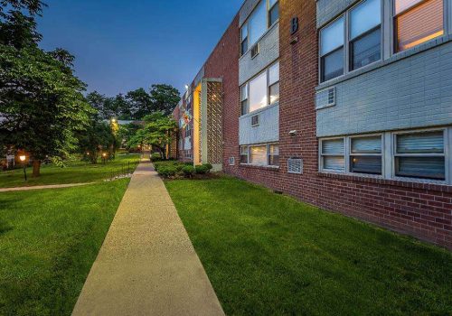 Walkway to residential brick buildings at Willow Bend apartments for rent in Philadelphia, PA