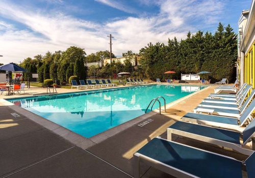 Outdoor pool with lounge chairs, tables, and umbrellas at Gateway Towers at Packer Park apartments